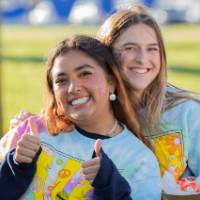 Two students wearing matching tye-dye t-shirts with a microphone and text that reads "Lakerpalooza"